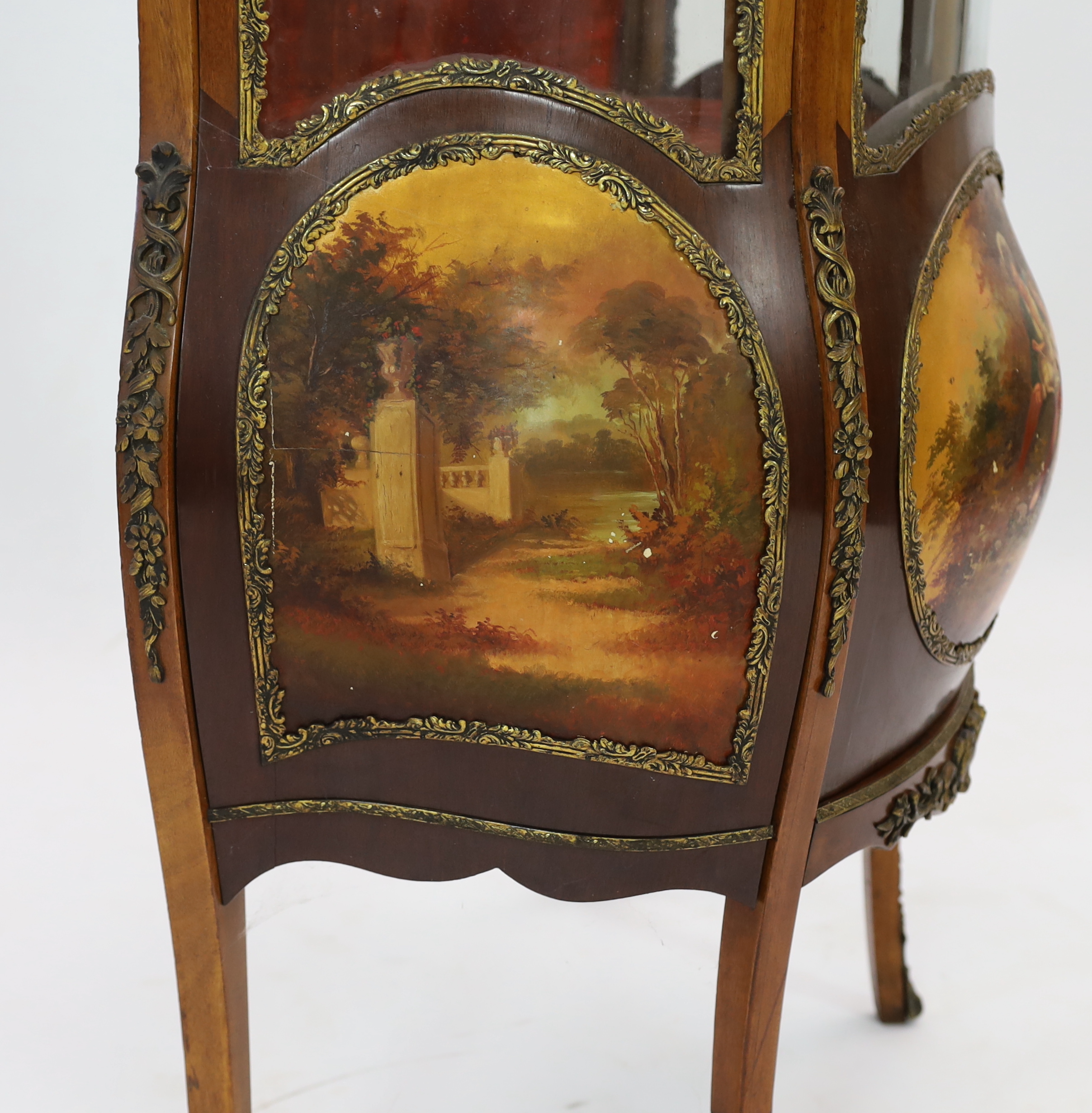 A French Vernis Martin style walnut vitrine, of bombé form with ormolu mounts, three quarter glazed door, lower panels, painted with scenes after Boucher and signed 'Albertine', on cabriole legs, 78cm wide, 42cm deep, 17